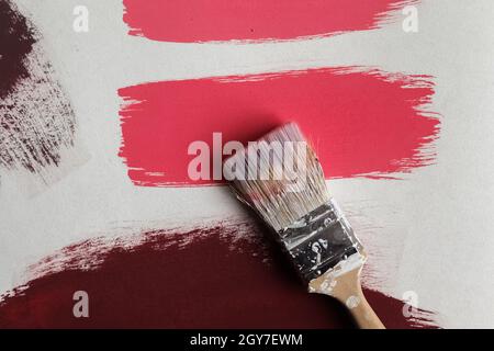 Concept of a paintbrush on a piece of paper with brush strokes with red and brown paint. Stock Photo