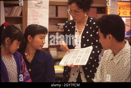 Austin Texas USA, April 1996: Vietnamese-American teacher holds parent-teacher conference with Vietnamese mother and father to talk about their young student's progress. ©Bob Daemmrich Stock Photo