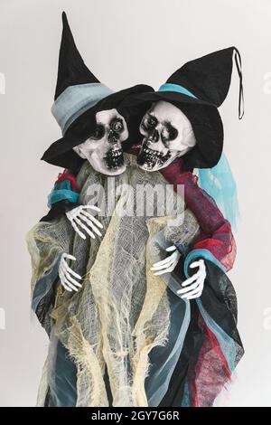 Two funny human skeletons, friendly hugging each other, ghosts in rags and hats. Halloween concept. Close-up. Verical.