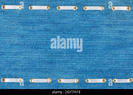 White satin ribbon inserted in the gold rings on blue denim, trendy background Stock Photo