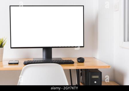 Computer monitor with white blank screen on the business desk with wireless mouse, keyboard at home office over white wall background, Photo of equipm Stock Photo