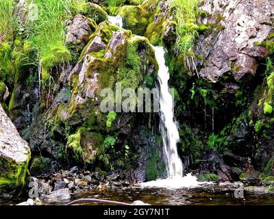 Waterfall from the thawed waters. Melting snow in the hilly tundra. Waterfall Stock Photo