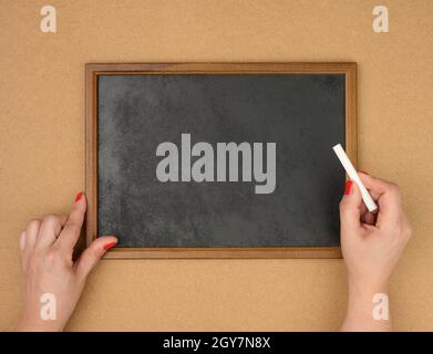 female hands and empty rectangular brown wooden frame on a brown background, copy space Stock Photo