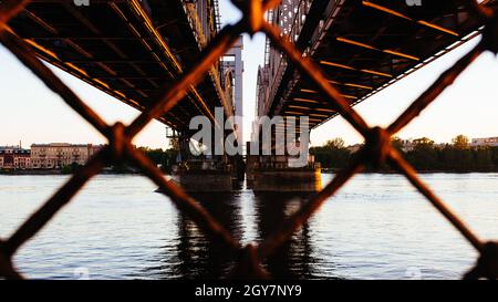 Closeup of a bridge over the river through a rusty cyclone fence Stock Photo