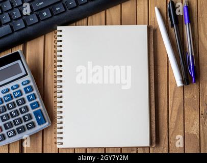 Blank Open Spiral Notebook With Calculator Keyboard Pen Placed Over Table. Stock Photo