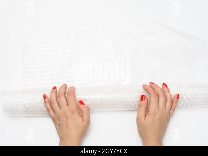 female hand holding crumpled piece of polyethylene with air bubbles on a white background, packing material Stock Photo
