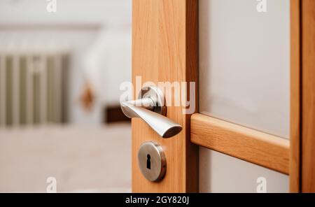 Opened modern wooden door into room, closeup detail on metal handle. Stock Photo