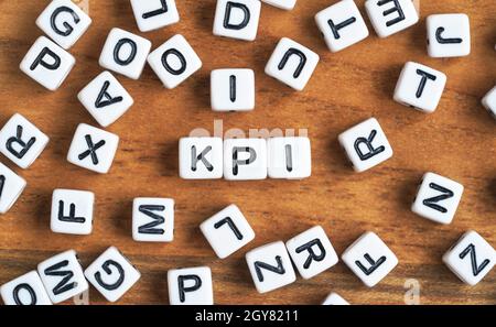 Small white and black bead cubes on wooden board, letters in middle spell KPI - Key Performance Indicators concept. Stock Photo