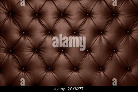 Close up background texture of dark brown capitone genuine leather, retro Chesterfield style soft tufted furniture upholstery with deep diamond patter Stock Photo