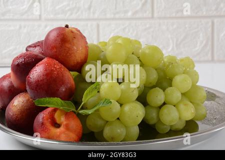 Fruit mix. Nectarine, grapes,  watermelon, melon. Pieces of fruit on a plate lie on a silver tray on white background. Stock Photo