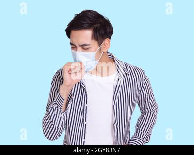 young man coughs and wears a protective medical mask to prevent infection Stock Photo