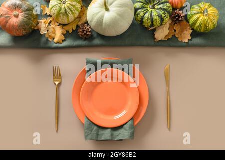 Autumn table setting decorated fall harvest with seasonal orange plate and golden cutlery for Thanksgiving day dinner. Flat layout. View from above. Stock Photo