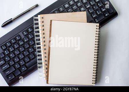 Two Plain Lined Spiral Notebooks With Pen And Keyboard On Table. Stock Photo