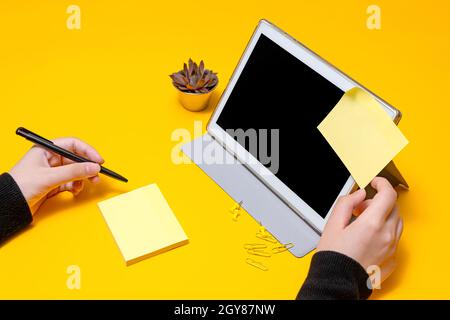 Woman Hand Holding Blank Notes Writing New Messege Updates Next To Tablet. Stock Photo