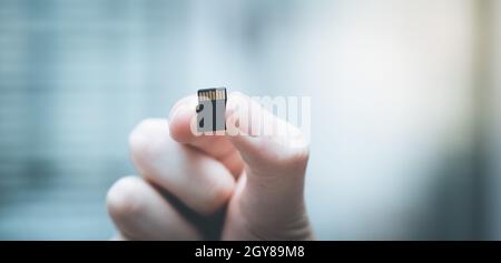 Young man is holding a tiny memory card in his hand, text space Stock Photo