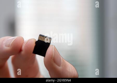 Young man is holding a tiny memory card in his hand, text space Stock Photo