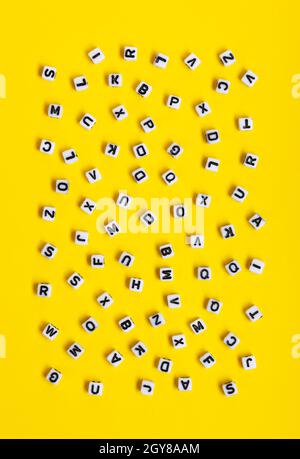 White cubes with letters scattered randomly on a yellow background. The Image can be used for many purposes, book covers or concepts relating to gramm Stock Photo