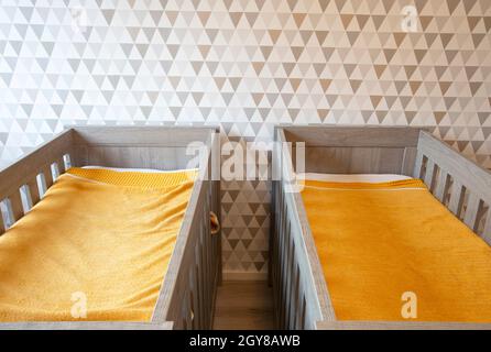 A Twin Bedroom with wooden baby beds for siblings, newborn babies modern stylish interior close up Stock Photo