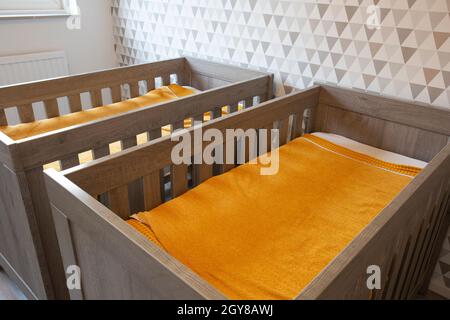 A Twin Bedroom with wooden baby beds for siblings, newborn babies modern stylish interior close up Stock Photo