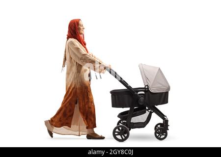 Full length profile shot of a woman wearing a hijab and pushing a baby stroller isolated on white background Stock Photo