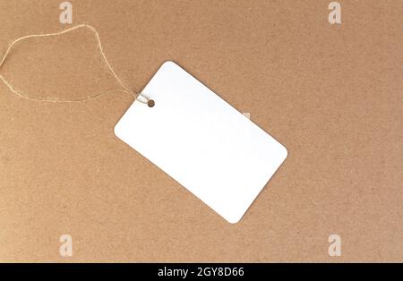 One blank white paper cloth label or price tag on brown background Stock Photo