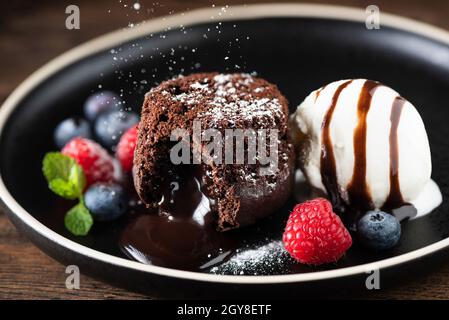 Chocolate fondant cake, molten lava cake with ice cream scoop and fresh berries on plate Stock Photo