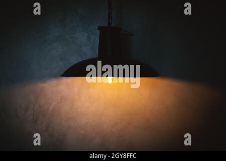 Black lamp and yellow light reflection on concrete wall Stock Photo