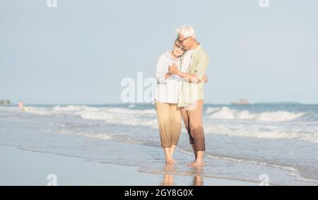 Happy Asian senior man and woman couple smile dancing resting relax on the beach honeymoon family sunny day, Romantic elderly enjoy travel summer vaca Stock Photo