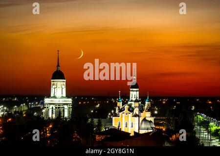 A church,temple or cathedral against the background of an evening sunset with a maroon sky and a big month.The horizon line at dawn with the moon and Stock Photo