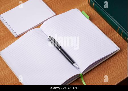 Plain Blank Open Notebooks With Stack Of Pens Container Over Table. Stock Photo