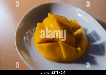 Diced mango on white plate above brown table Stock Photo