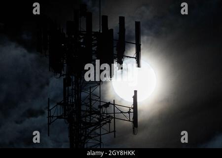 Harvest moon that is a full white moon with a tower silhouette in front of it and spooky wispy clouds Stock Photo
