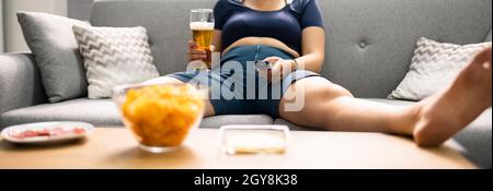 Overeating Junk Food, Drinking Beer And Watching TV Stock Photo