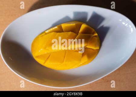 Diced mango on white plate above brown table Stock Photo