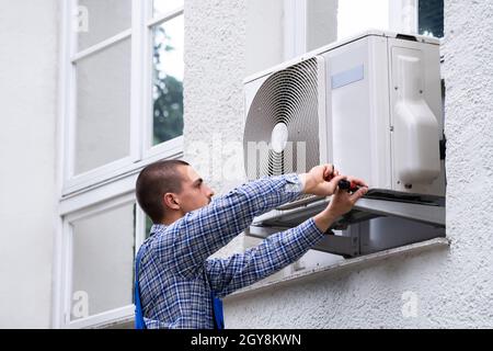 Technician Cleaning And Repairing Air Condition Appliance. AC Unit Maintenance Stock Photo