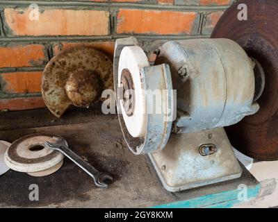 old electric grinding machine on workbench in rustic barn Stock Photo