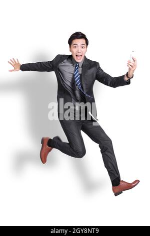 excited businessman jumping and holding mobile phone.  Isolated on white background. Stock Photo