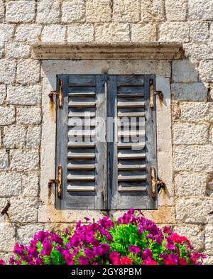 Old window with closed shutters decorated with flowers Stock Photo