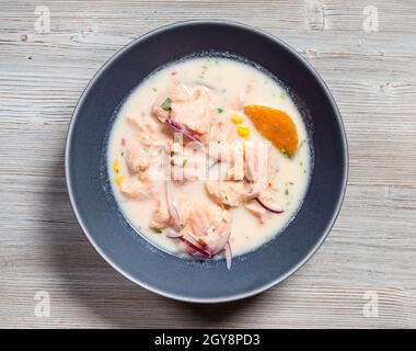 top view of peruvian Salmon ceviche in Leche de Tigre sauce with sweet potatoes and corn in bowl on gray wooden board Stock Photo