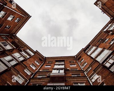 bottom view of gray clouds in sky between old brick house in Moscow city in autumn evening Stock Photo