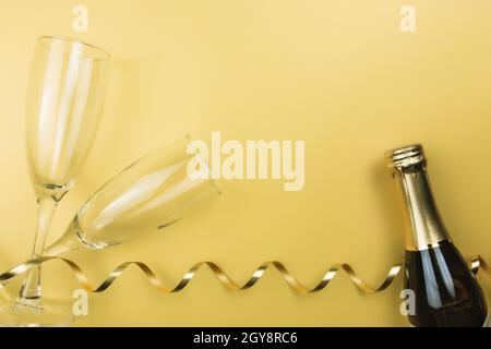 Glasses, sparkling wine bottle, ribbon, gold background. High quality photo Stock Photo