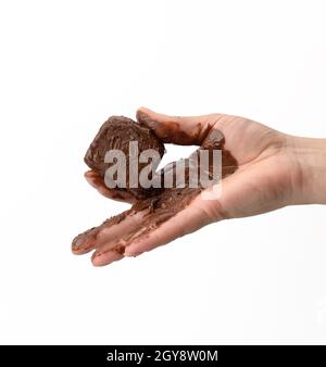 female hand holding a melted piece of dark chocolate, hand smeared with chocolate on a white background Stock Photo