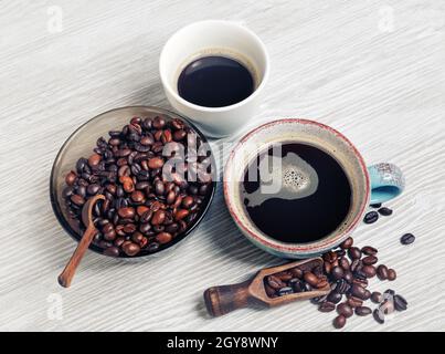 Photo of fresh tasty coffee on light wood table background. Coffee cups and coffee beans. Stock Photo