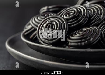 Spiral from liquorice candy on black plate. Stock Photo