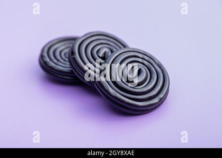 Spiral from liquorice candy on violet background. Stock Photo