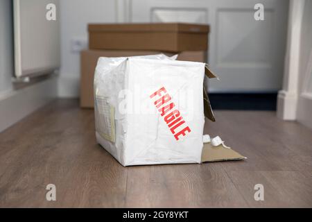 Beat up damaged delivery box with fragile sticker, broken deliverd cardboard packaging at home unhappy Stock Photo