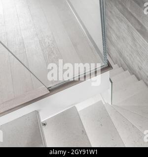 Modern design and innovative material. Microcement stairs with glass handrail. Stairs viewed from above. Glass railing. Stock Photo