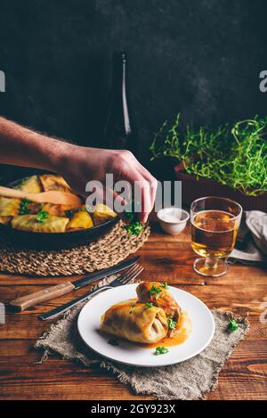 Cabbage Rolls Stuffed with Ground Beef on White Plate. Hand Garnish with Chopped Parsley Stock Photo