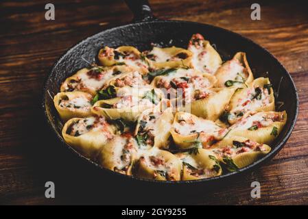 Skillet of baked jumbo shells pasta stuffed with ground beef, spinach and cheese Stock Photo