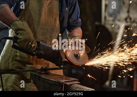 Close-up of worker using electric grinder to polish detail in the workshop Stock Photo
